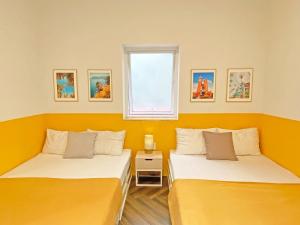 Duas camas num quarto com paredes amarelas em The Bay - Ha Long Homestay em Ha Long