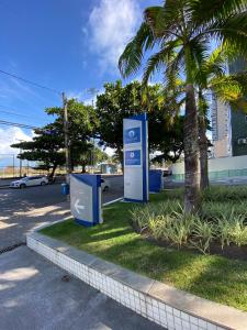 a parking lot with two signs next to a palm tree at Beach Class Internacional apartamento in Recife
