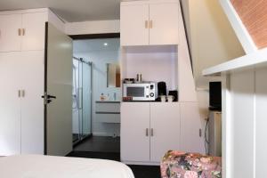 ein Schlafzimmer mit weißen Schränken und einer Mikrowelle in der Unterkunft Hotelhuisjes Aartswoud in Aartswoud