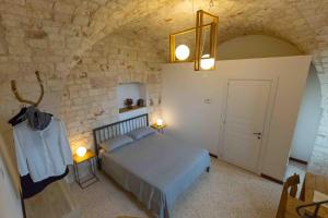 a bedroom with a bed and a stone wall at Da Concavo e Convesso in Locorotondo