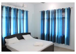 a bedroom with blue curtains and a bed with at Kishkindha Wild 3BHK in Rāmnagar