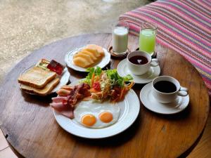 a wooden table topped with plates of breakfast foods and cups of coffee at Wualai Boutique by Lanna Oriental in Chiang Mai