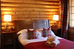 a bedroom with a bed with two lamps and two towels at Bunnahahbain - Two Bedroom Luxury Log Cabin with Private Hot Tub in Berwick-Upon-Tweed