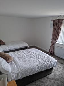 a bedroom with two beds and a window at 3 bedroom house-Ellesmere Port in Ellesmere Port