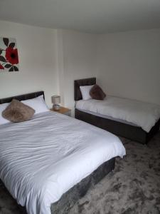 um quarto com 2 camas e lençóis brancos em 3 bedroom house-Ellesmere Port em Ellesmere Port