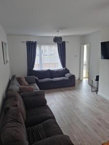 a living room with a large couch and a large window at 3 bedroom house-Ellesmere Port in Ellesmere Port