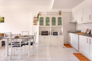 a kitchen with white cabinets and a table with chairs at ALTIDO Deluxe apt with terrace in Costa da Caprica in Costa da Caparica