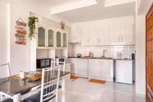 a white kitchen with white cabinets and a table at ALTIDO Deluxe apt with terrace in Costa da Caprica in Costa da Caparica