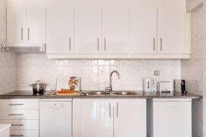 a white kitchen with white cabinets and a sink at ALTIDO Deluxe apt with terrace in Costa da Caprica in Costa da Caparica