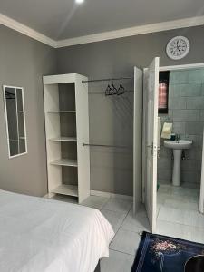 a bedroom with a bed and a bathroom with a sink at WILLOW GUEST HOUSE in Boksburg