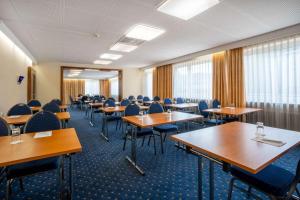 una sala de conferencias con mesas, sillas y ventanas en Styles Hotel Unterföhring, en Múnich