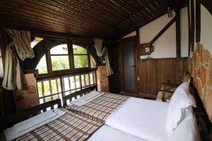 a bedroom with a bed in a room with windows at Hotel Nasho Vruho in Berat