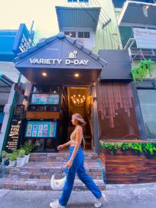 a woman walking down a street in front of a store at VarietyD-DayHostel HuaHin in Hua Hin