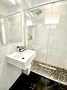 biała łazienka z umywalką i prysznicem w obiekcie Hotel Ducale w Rimini