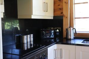 a kitchen with black counter tops and white cabinets at Strathisla - Luxury Two Bedroom Log Cabin with Private Hot Tub & Sauna in Berwick-Upon-Tweed