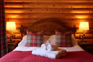 una camera da letto con un letto con due asciugamani e due lampade di Strathisla - Luxury Two Bedroom Log Cabin with Private Hot Tub & Sauna a Berwick-Upon-Tweed
