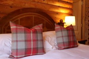 a bed with two red and gray pillows on it at Strathisla - Luxury Two Bedroom Log Cabin with Private Hot Tub & Sauna in Berwick-Upon-Tweed