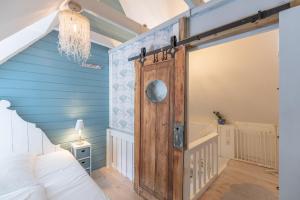 a bedroom with a wooden door in a room with blue walls at Dat lüttje Reethus in Ockholm