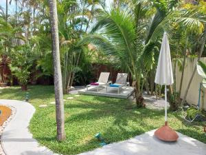 拉威海灘的住宿－Villa Paradise Island，庭院设有两把椅子和一把遮阳伞,并种植了棕榈树。