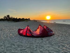 a red kite laying on the beach at sunset at BEACH HOUSE - Suite 1 - NA PRAIA - BEACHFRONT in Barra Grande