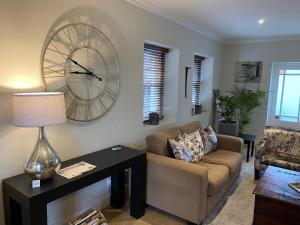 a living room with a couch and a clock on the wall at Plumwood Boutique Hotel by The Living Journey Collection in Franschhoek