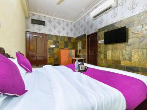 a large white bed with purple pillows and a flat screen tv at The Maurvi Inn in Jaipur