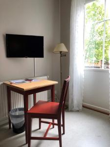Habitación con escritorio con silla y TV. en Finnåkers Kursgård, en Finnåkers Bruk