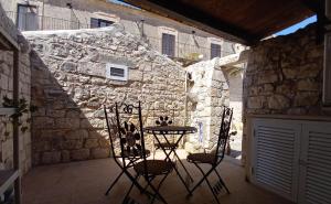 um pátio com 2 cadeiras e uma mesa em frente a uma parede de pedra em Agriturismo Villa Flavia em Casa Serrafiori