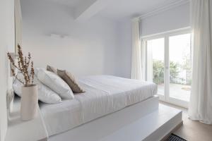 a white bedroom with a white bed and a window at Citadela Paros Molos - Beachfront Maisonette with Plunge Pool in Molos Parou