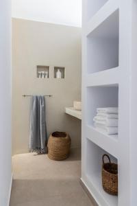 a bathroom with white shelves with towels and a basket at Citadela Paros Molos - Beachfront Maisonette with Plunge Pool in Molos Parou
