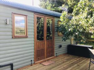 ein Haus mit einer Holztür und einer Terrasse in der Unterkunft The Hut in the Orchard @ Yorecroft in Aysgarth