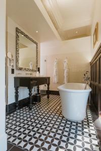 ein Badezimmer mit Badewanne, Waschbecken und Spiegel in der Unterkunft The LaLit London in London