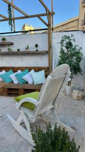 a white chair sitting on a patio with pillows at Hostel On in Sliema
