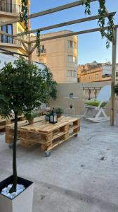 a patio with a wooden bench and a potted tree at Hostel On in Sliema