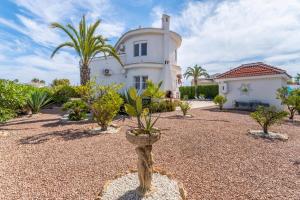 a large white house with palm trees in a yard at Modern villa with great location in Ciudad Quesada