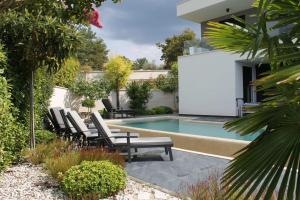 a backyard with a pool with chairs and a white screen at Luxury Villa Ane in Malinska +79 photos