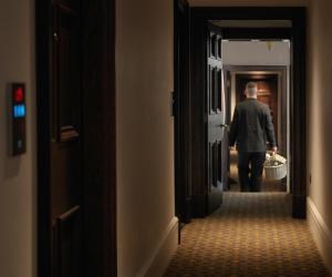 The LaLit London - Small Luxury Hotel of the World في لندن: رجل يمشي في الممر مع سلة