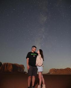 a man and woman standing on the beach under the stars at stars magic camp in Wadi Rum