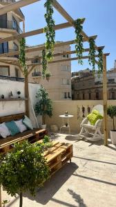 a rooftop patio with benches and a pergola at Hostel On in Sliema