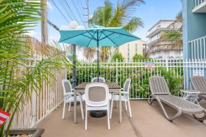 um pátio com uma mesa, cadeiras e um guarda-sol em Coastal Palms Inn and Suites em Ocean City