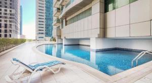 a swimming pool with a chair and a building at SKY NEST HOMES PRIVATE 1 BEDROOM APARTMENT DUBAI MARINA in Dubai