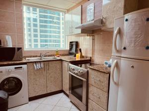 a kitchen with a white refrigerator and a dishwasher at SKY NEST HOMES PRIVATE 1 BEDROOM APARTMENT DUBAI MARINA in Dubai