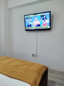 TV de pantalla plana colgada en una pared junto a la cama en Simona Apartament Palas Mall 1, en Iaşi