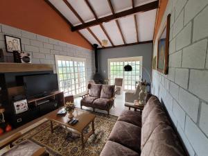 a living room with a couch and a brick wall at Casa Mirante Bixo Do Mato in Muçum