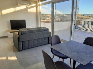 a living room with a couch and a table with chairs at Panoramic Penthouse Haven in Mellieħa