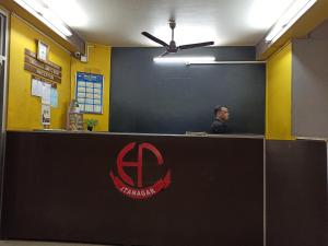 un hombre sentado en un mostrador en una oficina en Hotel Aane en Itānagar