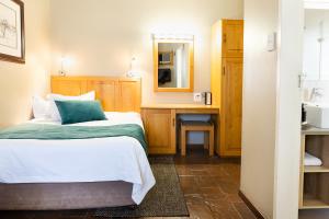 a bedroom with a bed and a desk and a mirror at Kathu Gamagara Lodge in Kathu