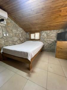 1 dormitorio con cama y pared de piedra en Zeytindağı bungalow, en Mehmetalanı