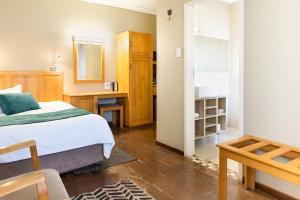 - une chambre avec un lit, un bureau et un miroir dans l'établissement Kathu Gamagara Lodge, à Kathu