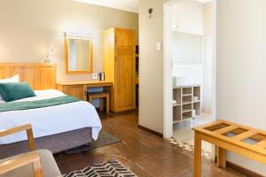 a bedroom with a bed and a desk and a mirror at Kathu Gamagara Lodge in Kathu